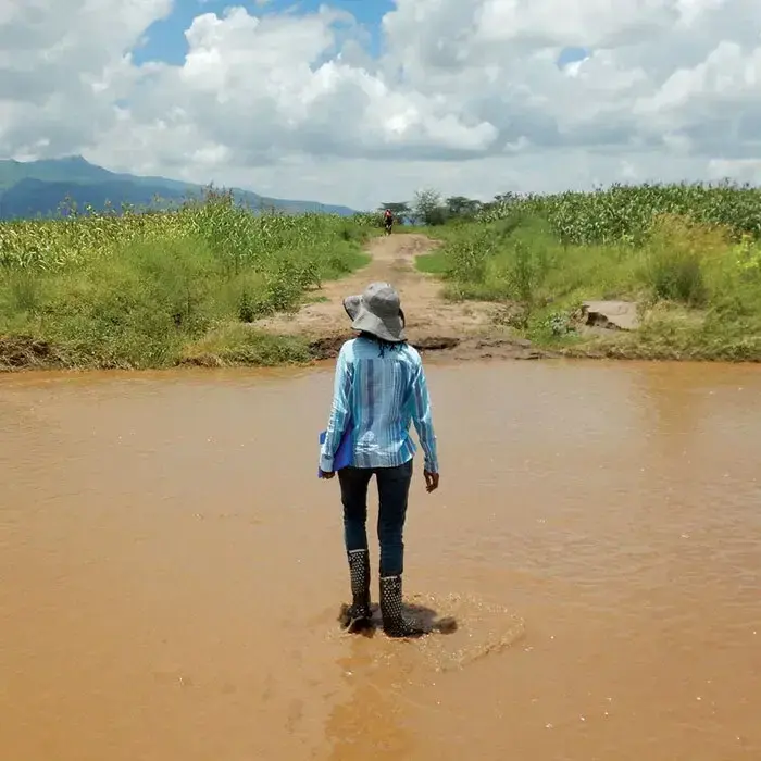 Researcher Catherine Nakalembe stands in muddy water facing away from the camera