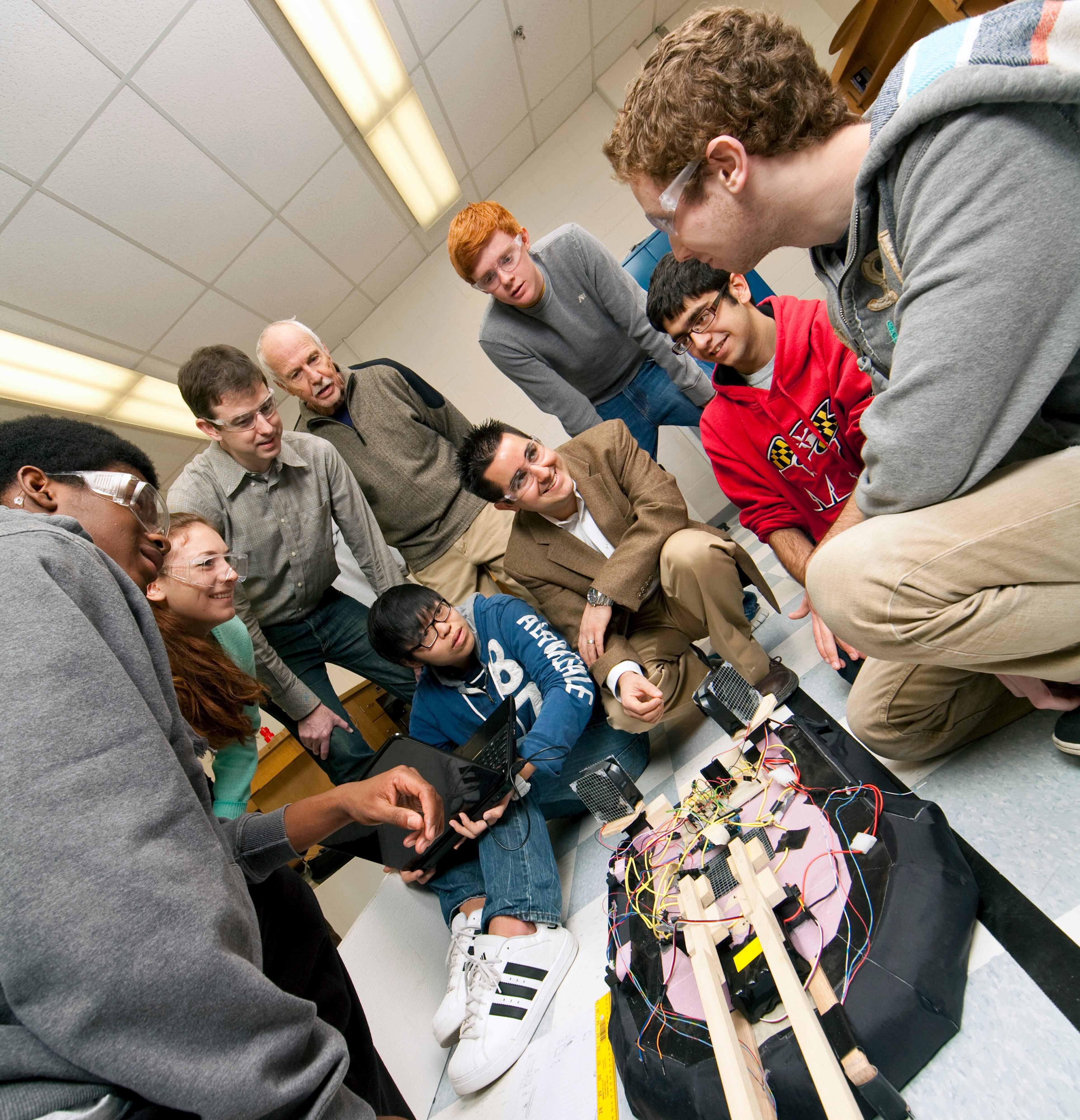 Undergraduate students test a hovercraft design with two advising faculty members