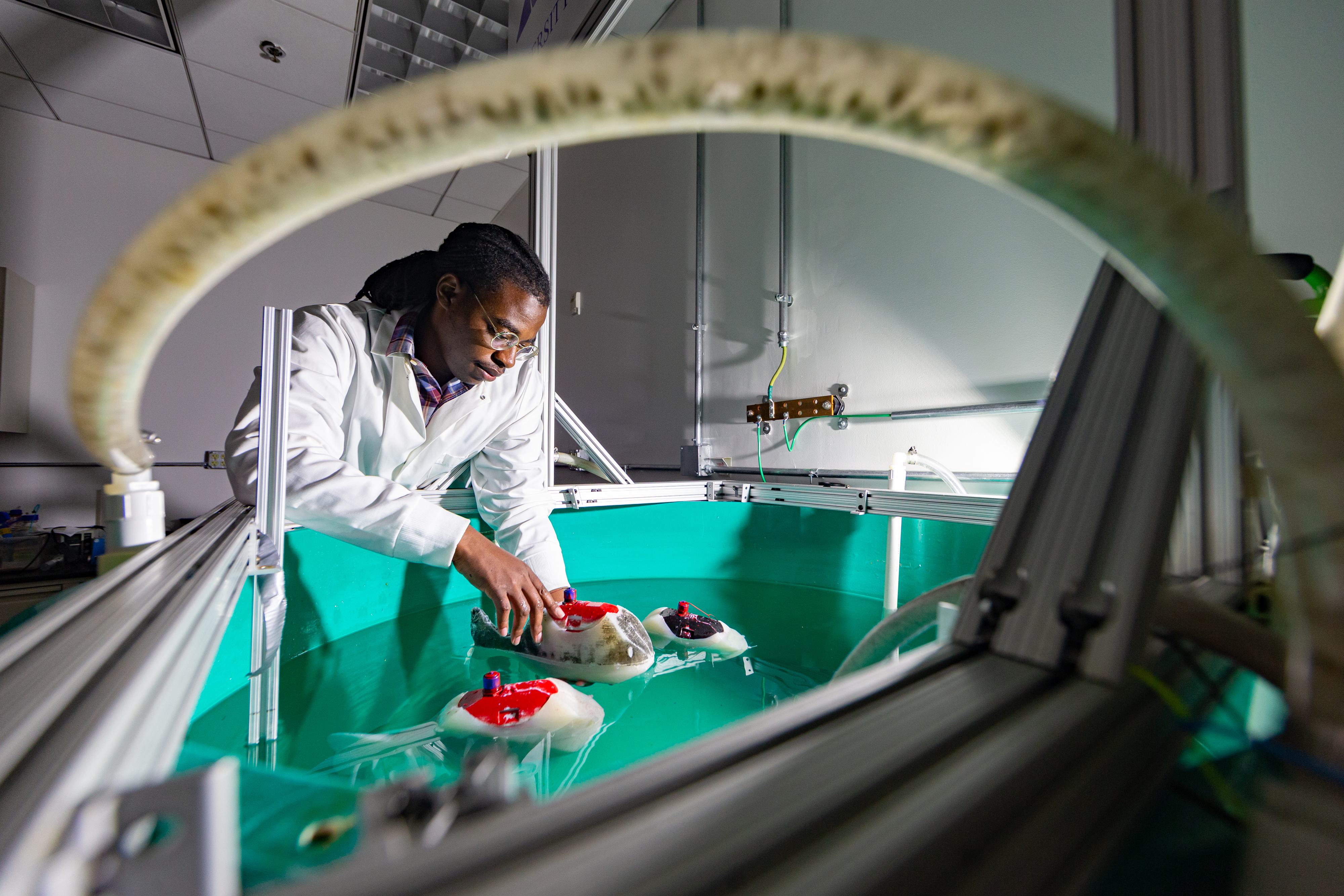 "Anthony Thompson, Aerospace Engineering ’23 PhD Candidate, poses with robotic “Flexifish.”