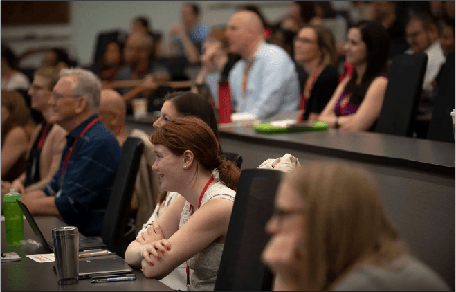 Faculty and staff smile as they look on in a meeting room during the UMD Social conference